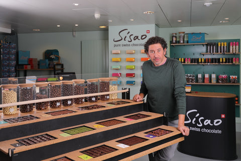 Ahmed Atmani dans la boutique Sisao, comptoir de dégustation avec bonbons et tablettes de chocolat suisse artisanal